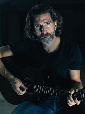 Porträtfoto von Dr. Timo Eifert mit Gitarre